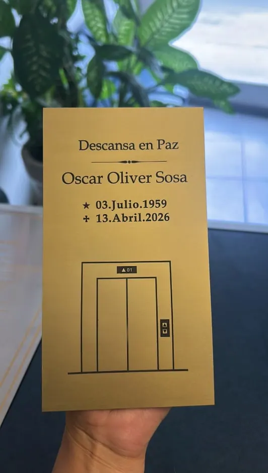 Placa dorada con nombre, fechas y el dibujo de un elevador
