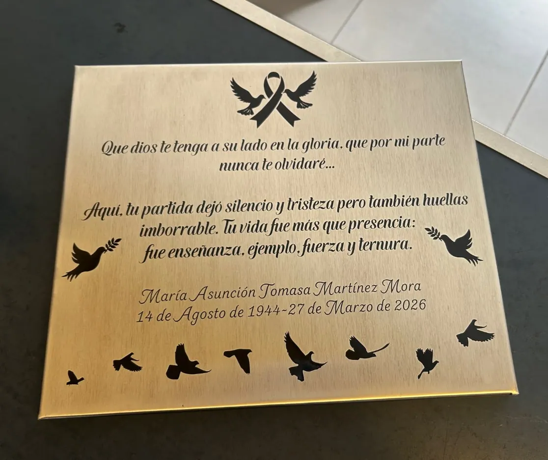 Placa dorada con un poema, aves y un nombre grabados