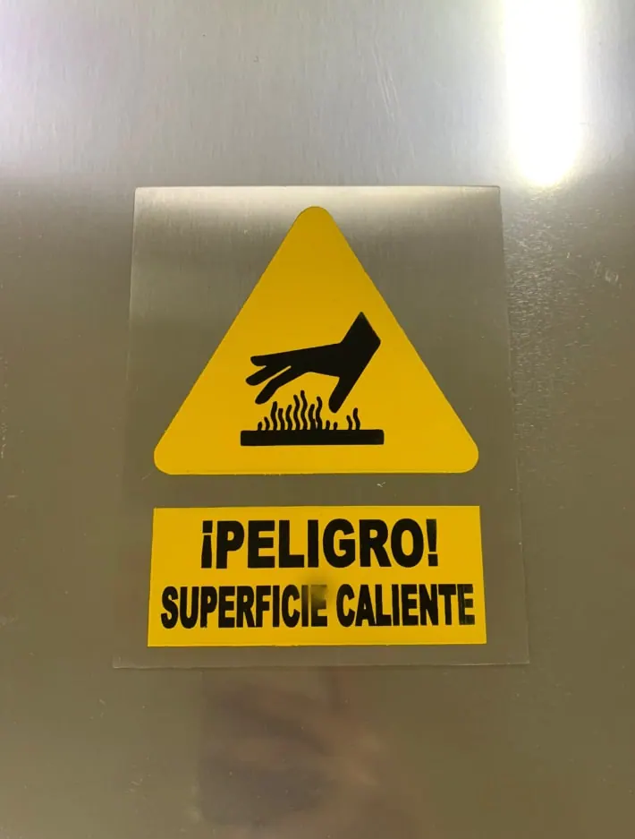 Placa de advertencia de superficie caliente sobre acero cepillado