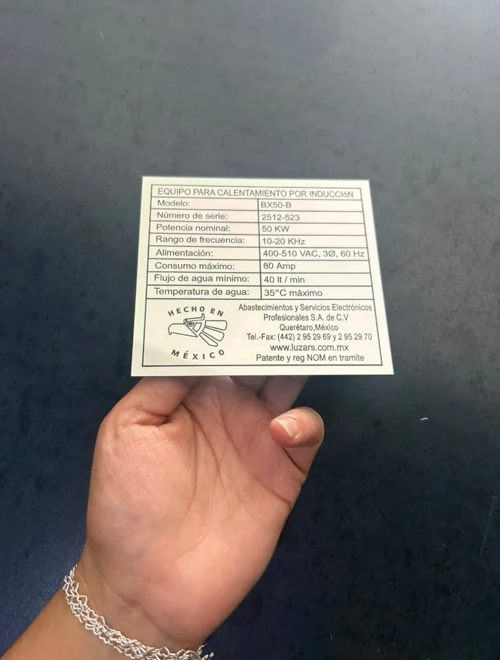 Placa de datos técnicos de un equipo, sostenida en la mano