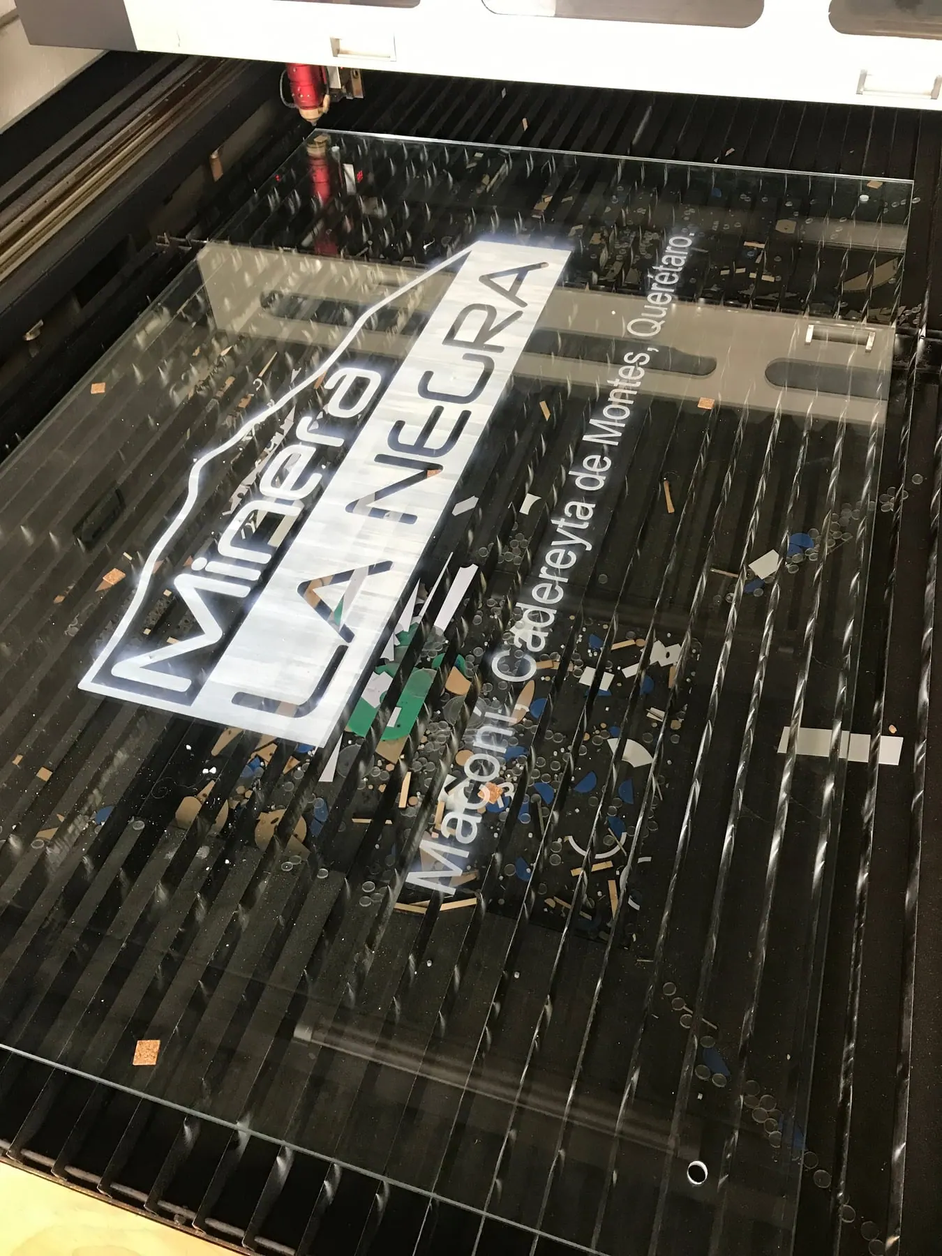 Letrero de acrílico recién cortado, todavía sobre la cama de la máquina láser